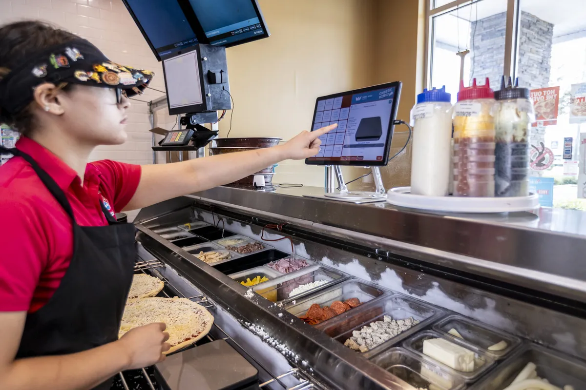 Kitchen staff member using the Portion King tablet at the topping prep line
